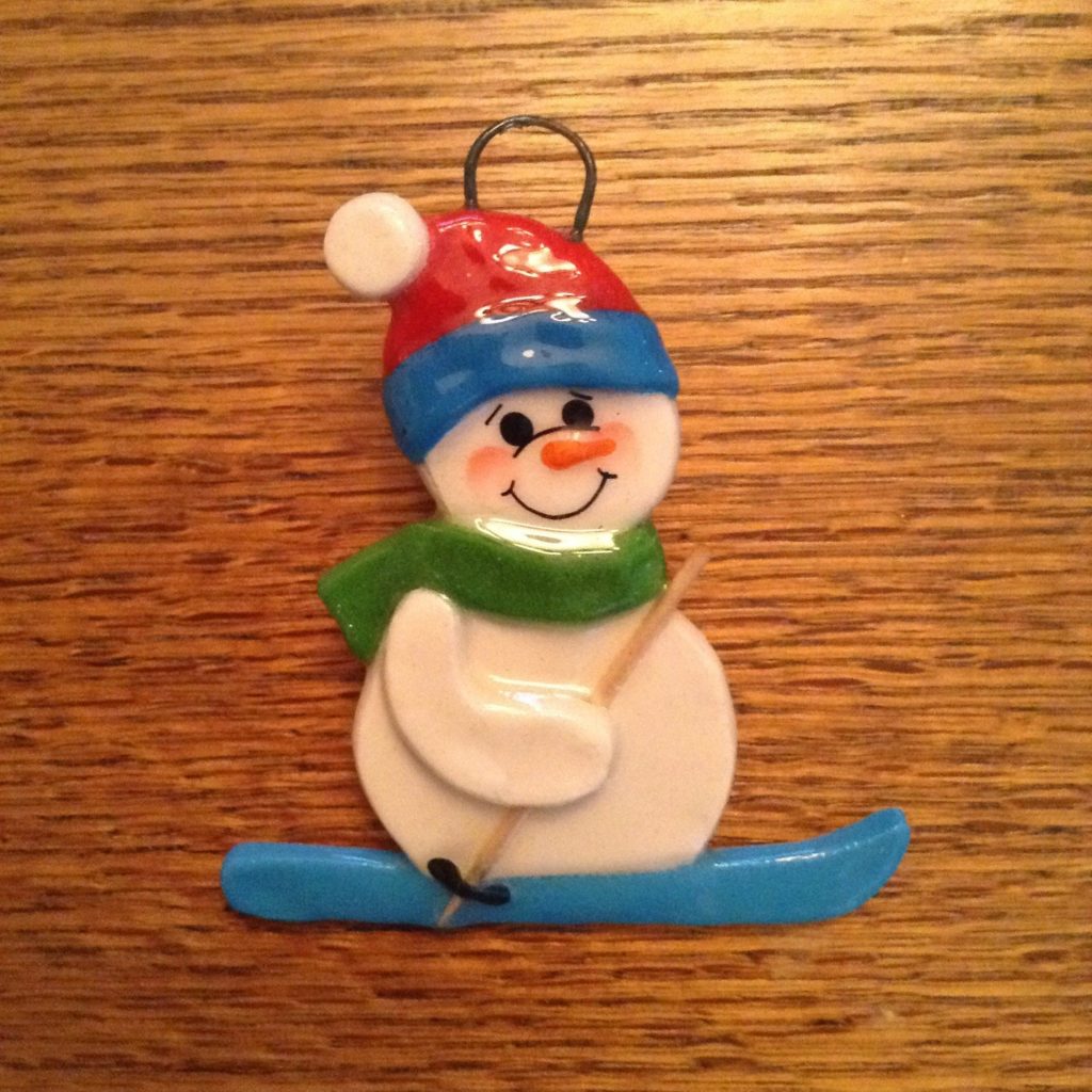 A snowman ornament is sitting on skis.