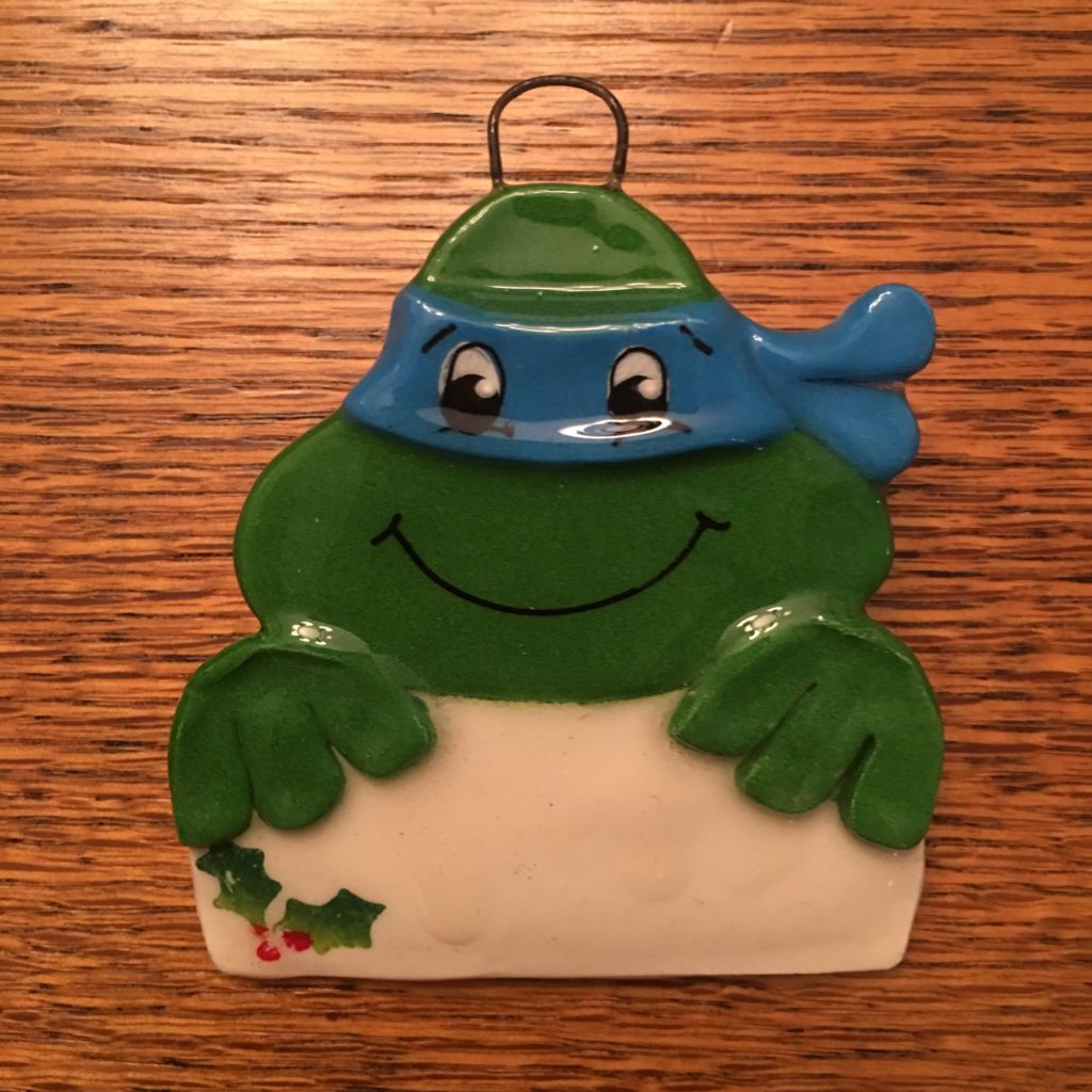 A turtle ornament with a blue hat and green shirt.