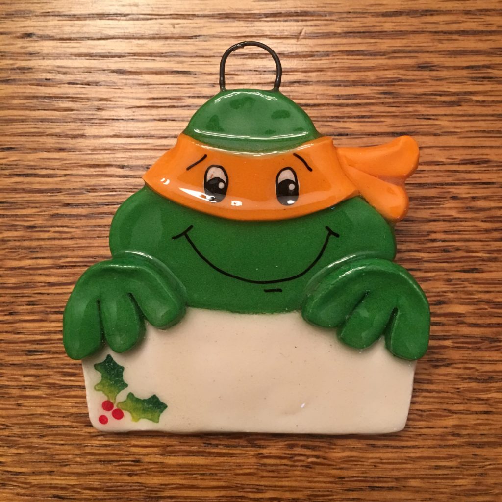 A turtle ornament with a sign hanging on the back.