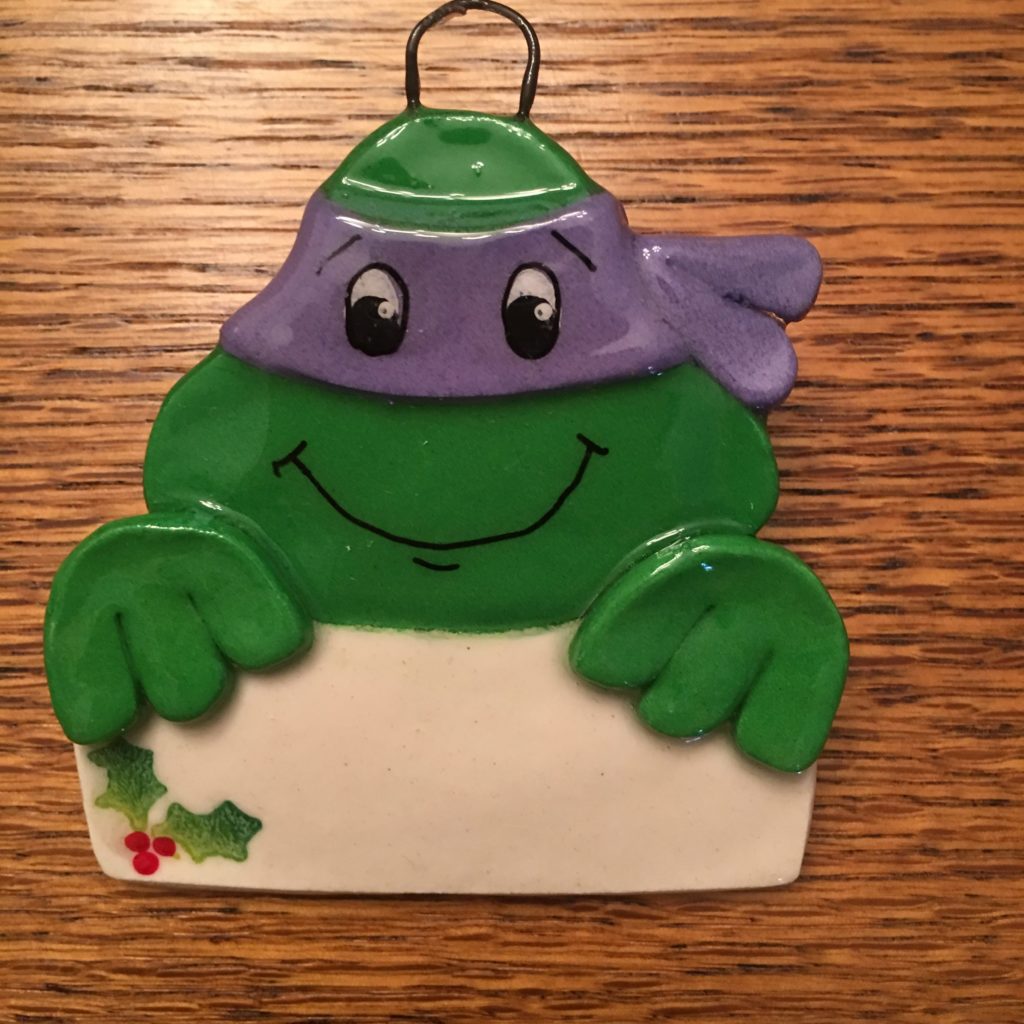 A green frog with a purple hat holding a sign.
