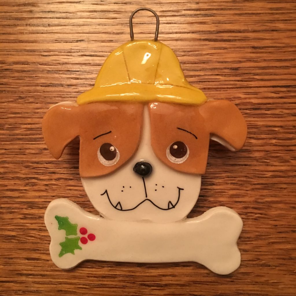A dog ornament with a yellow hat and bone.