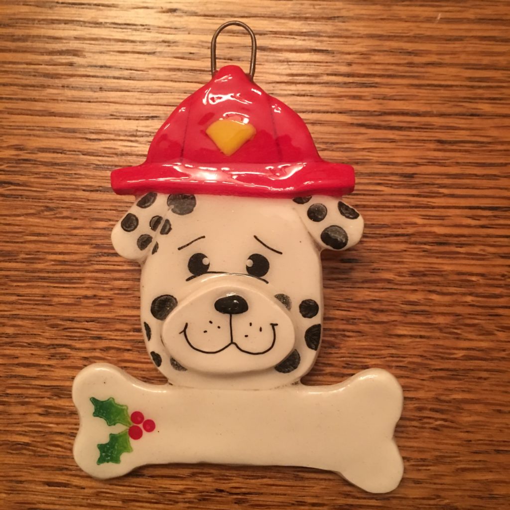A dalmatian dog ornament with a fire hat and bone.