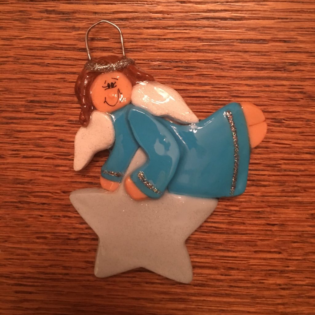 A blue angel ornament sitting on top of a star.