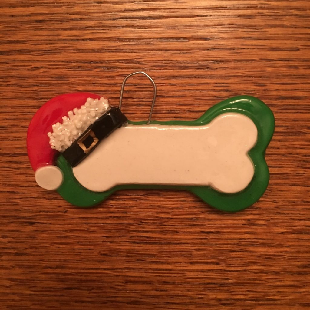A dog bone ornament with santa 's hat on it.