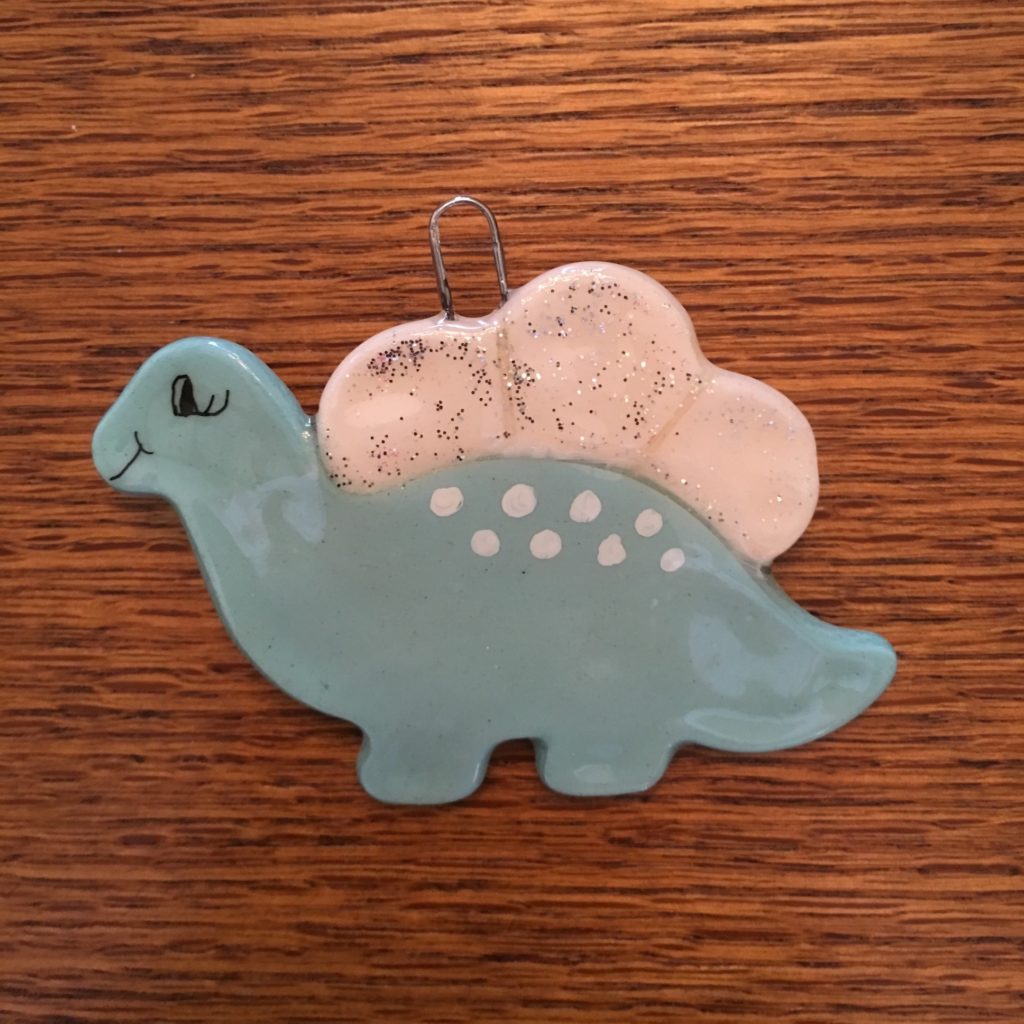 A blue dinosaur ornament sitting on top of a wooden table.