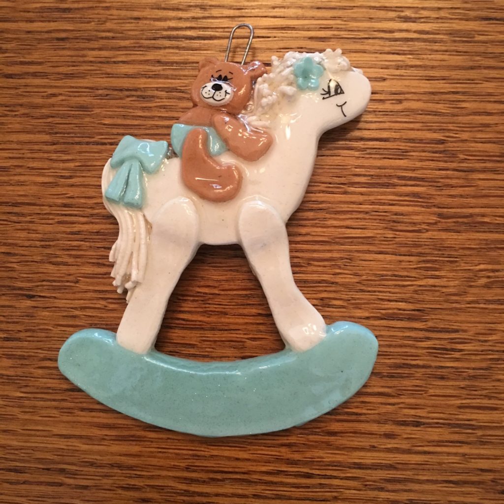 A white and blue horse ornament on top of a wooden table.