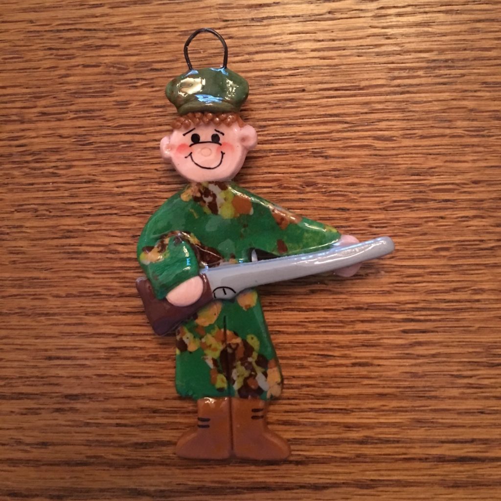 A toy soldier holding a gun on top of a wooden table.