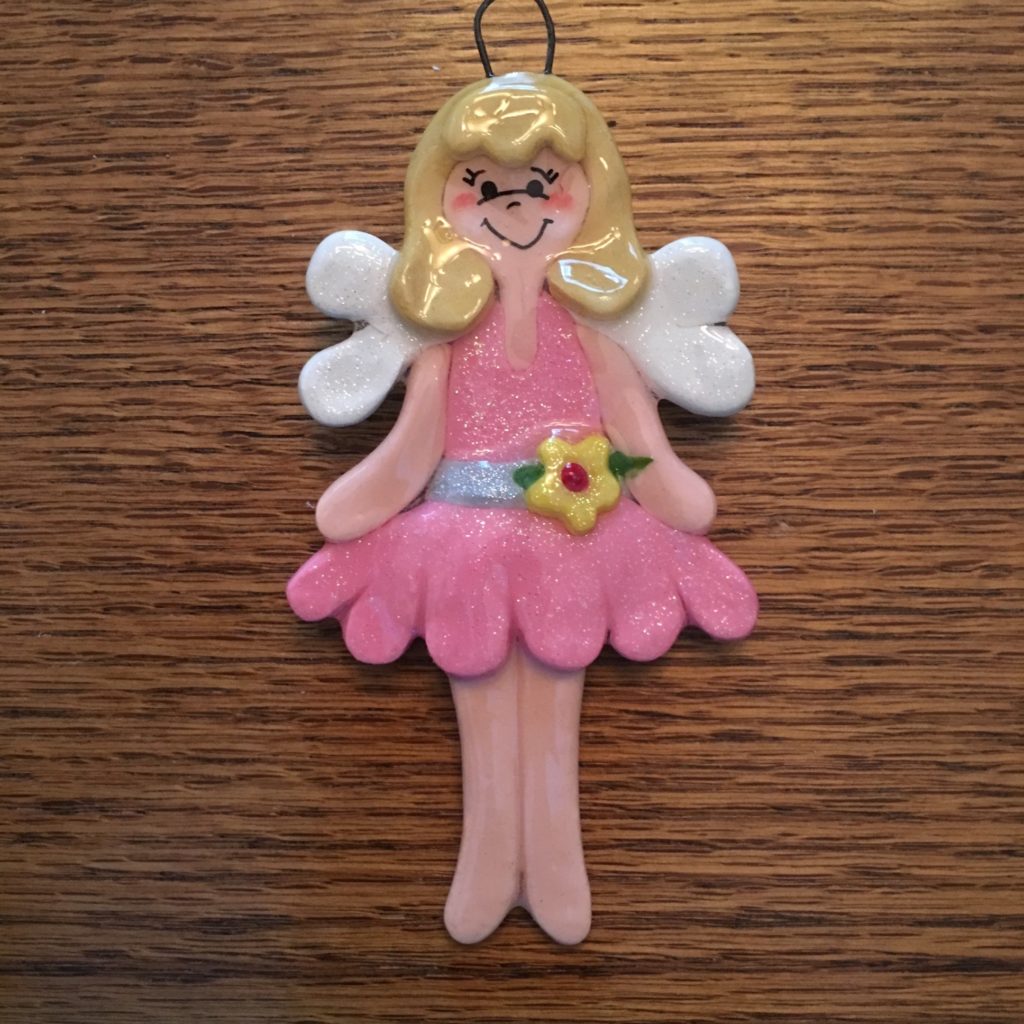 A pink and white fairy ornament on top of a wooden table.