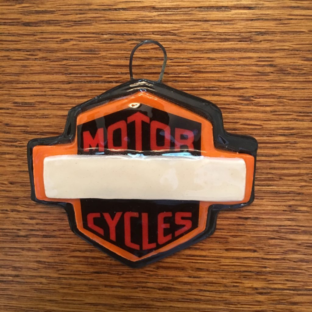 A harley davidson ornament is hanging on the wall.