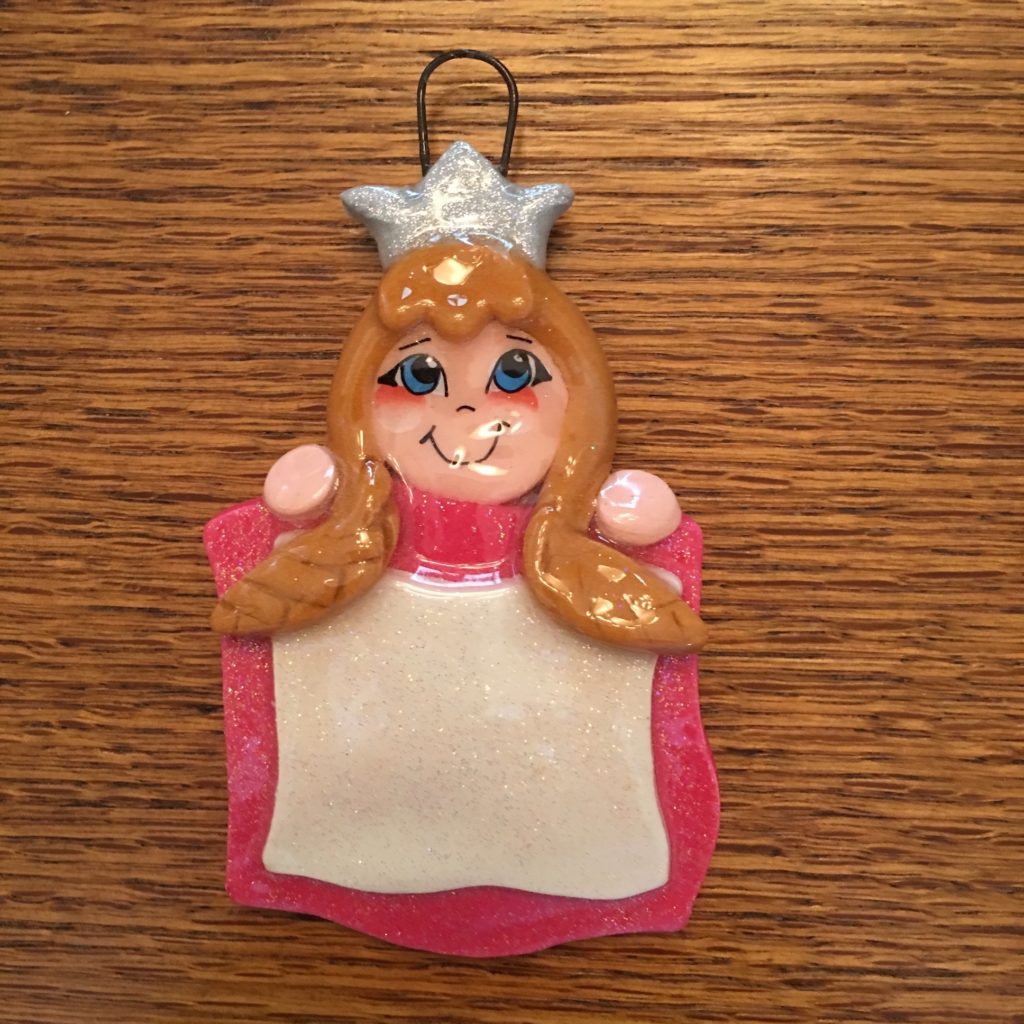 A pink ornament with a girl 's face and crown.