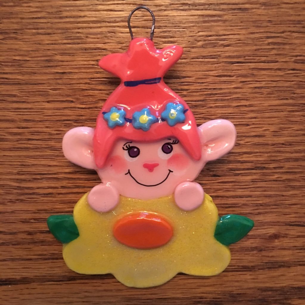 A pink and yellow clown ornament sitting on top of a wooden table.