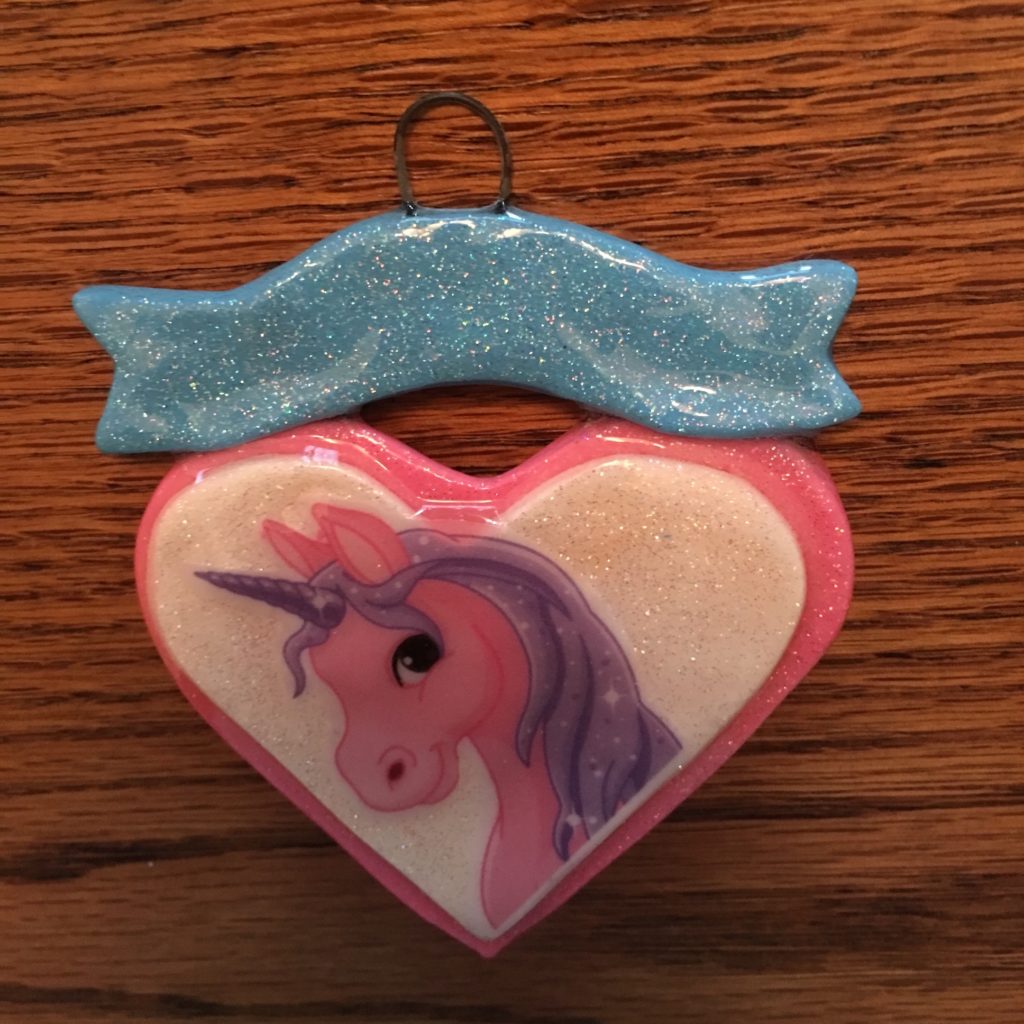 A heart shaped ornament with a unicorn on it.