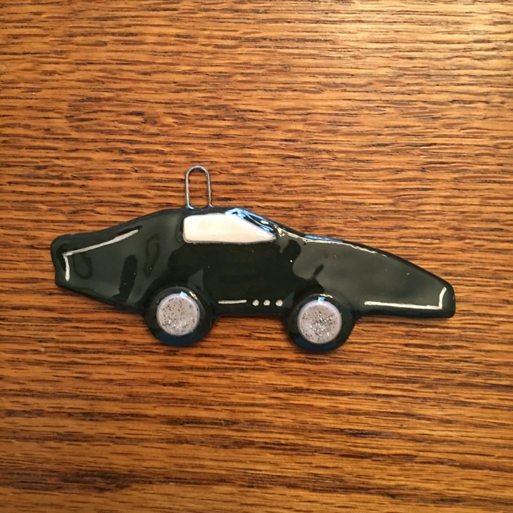 A black car ornament is sitting on top of a wooden table.