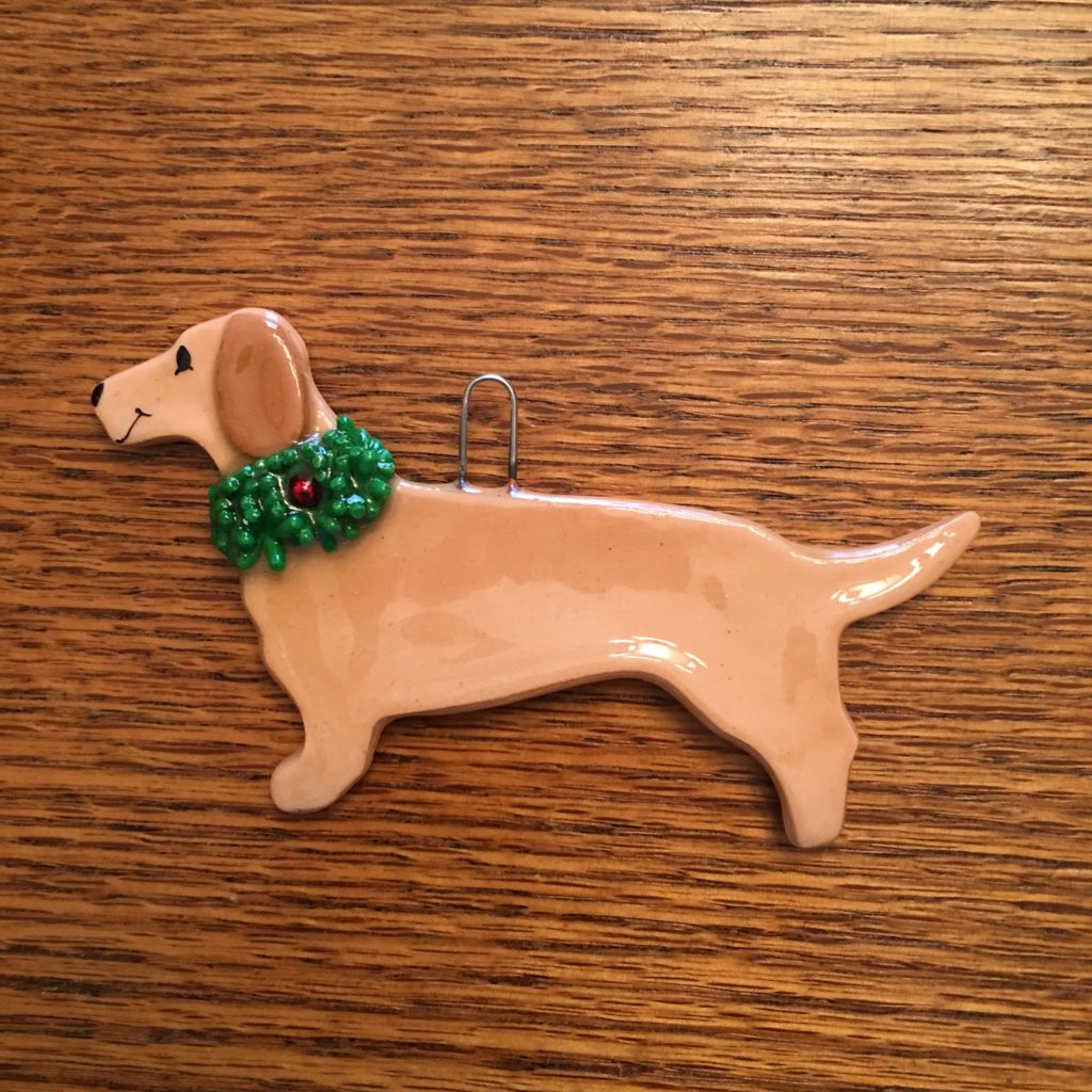 A dog ornament with a green bow on it.