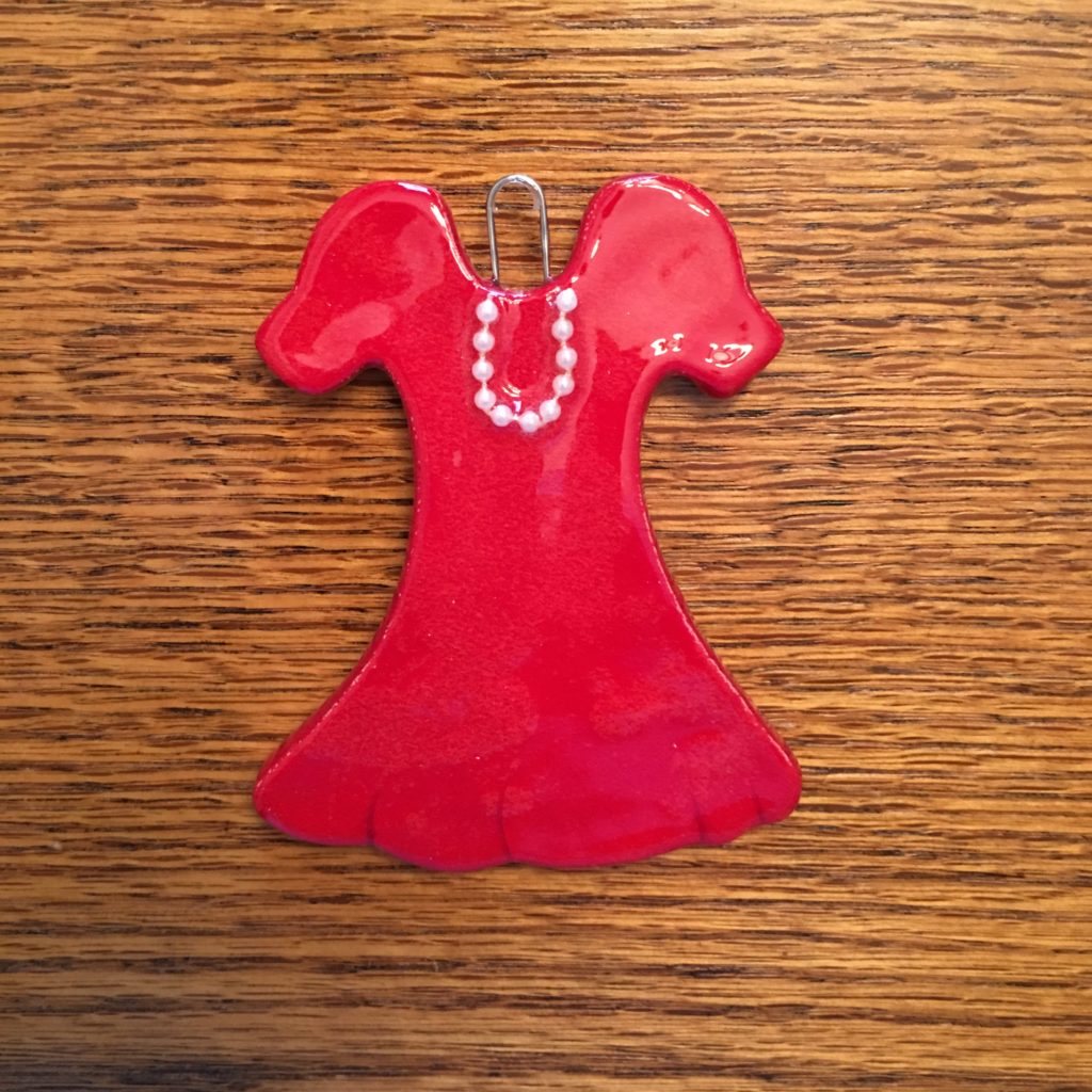 A red dress ornament is sitting on the table.