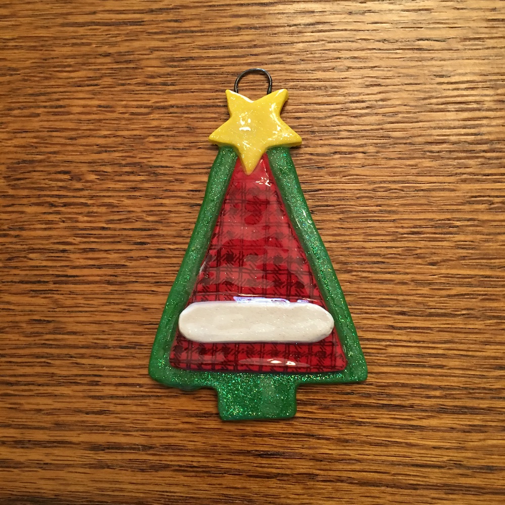 A christmas tree ornament is hanging on the wall.