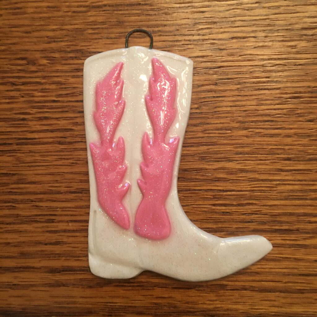 A white cowboy boot with pink lobster design.