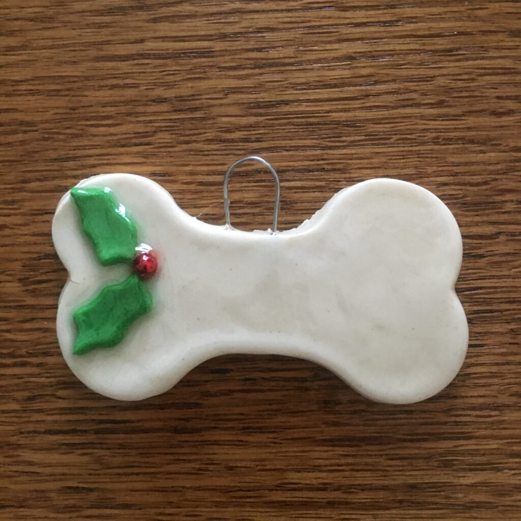 A dog bone ornament with holly on it.