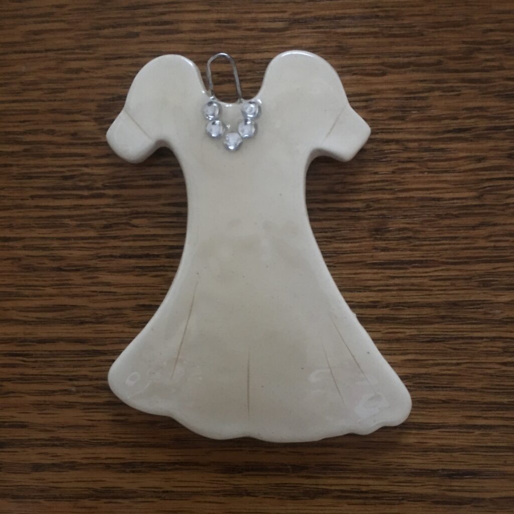 A white dress ornament sitting on top of a wooden table.