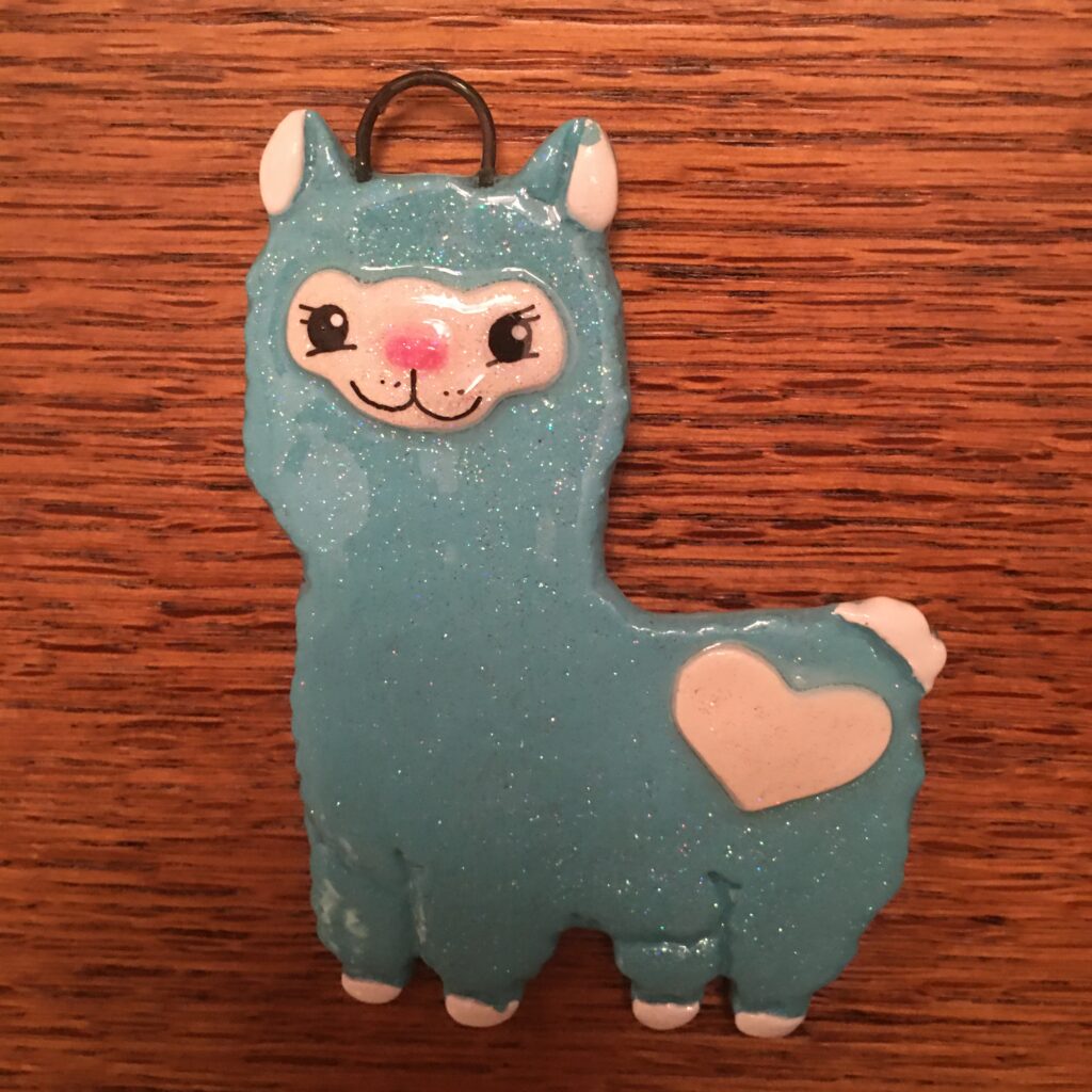 A blue llama ornament with a heart on it's head.