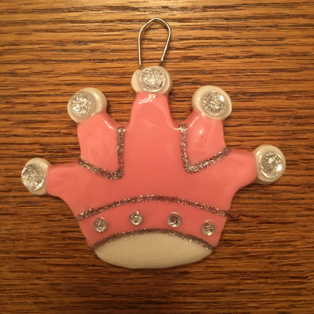 A pink crown ornament on top of a wooden table.