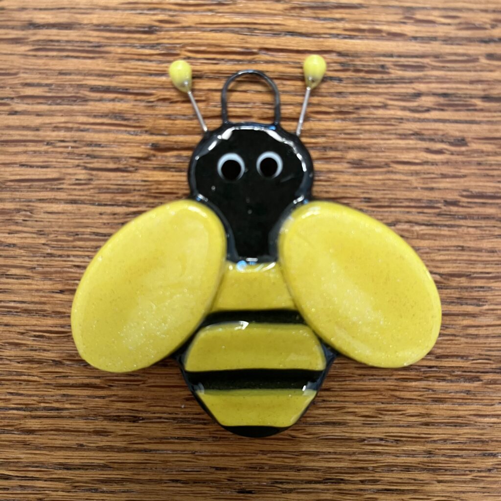 A bee pin sitting on top of a wooden table.