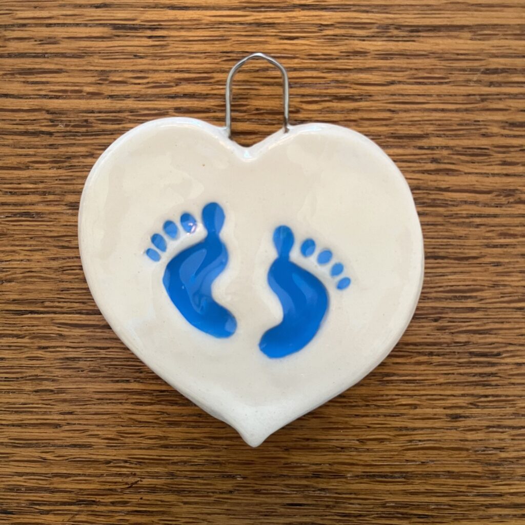 A heart shaped ornament with blue footprints on it.