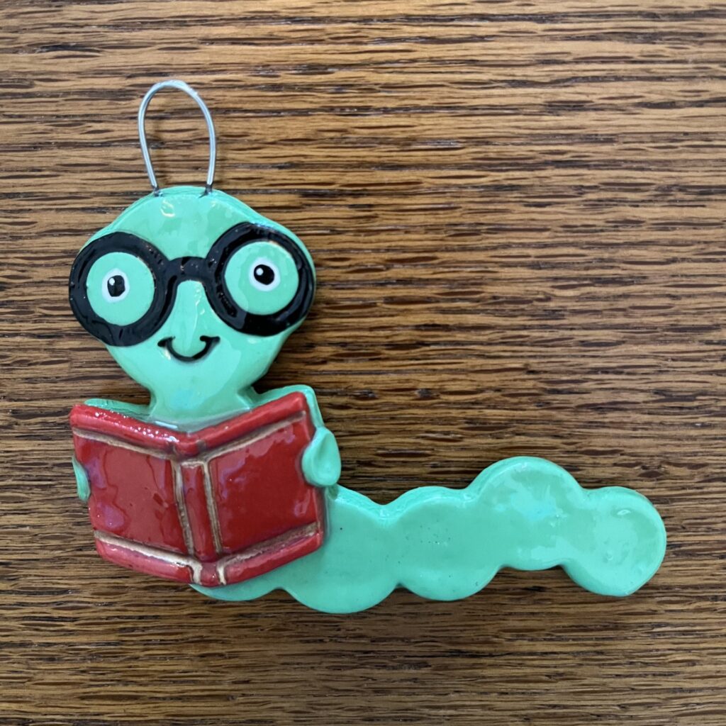 A green worm with glasses and a book.