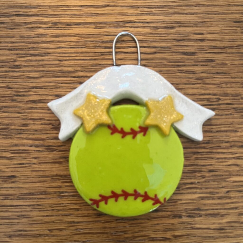 A softball ornament with two stars on it.