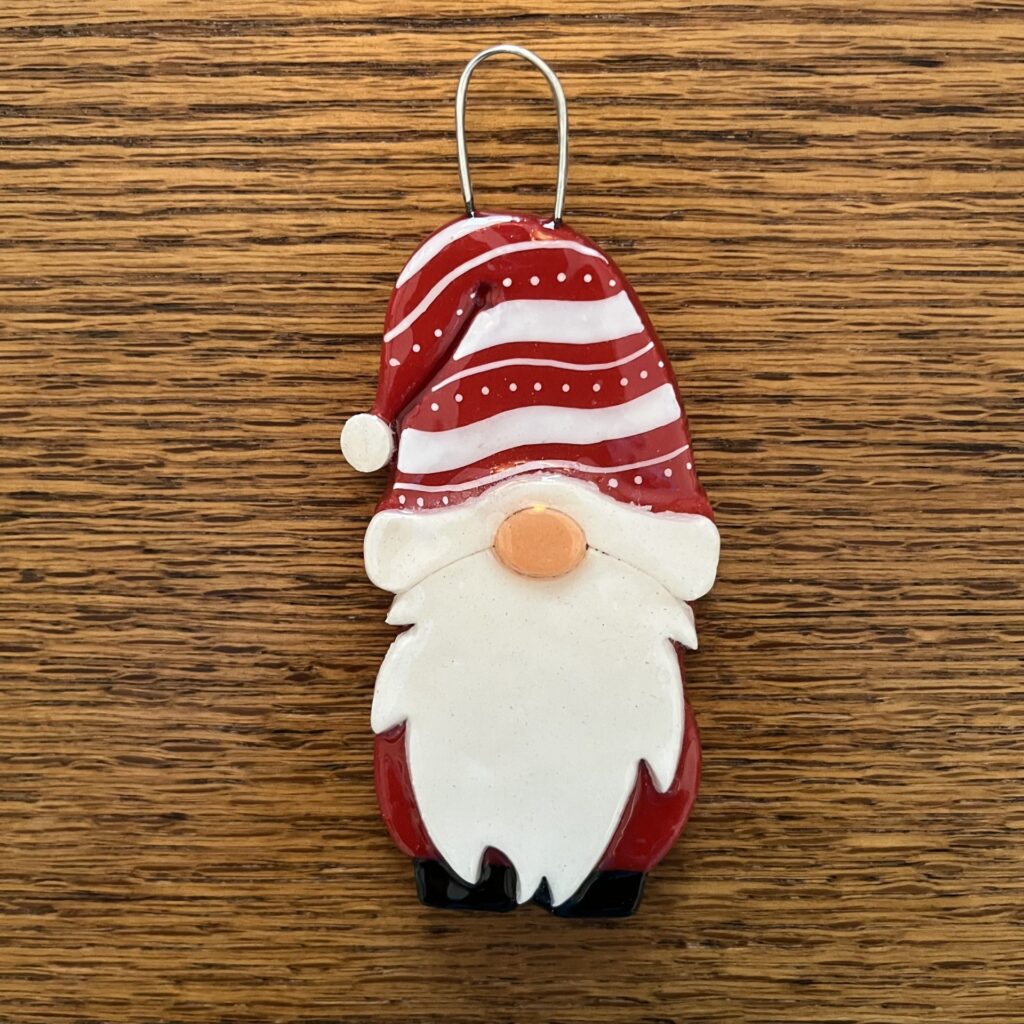 A red and white gnome ornament on top of a wooden table.